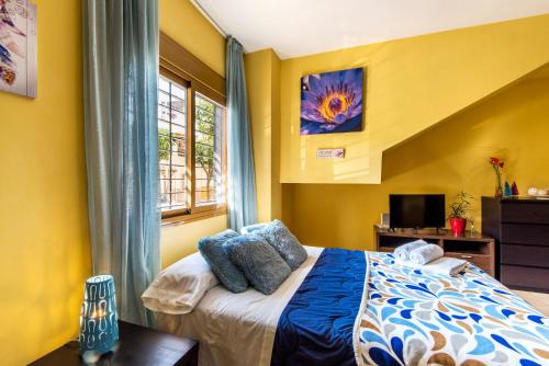 a bedroom with yellow walls and a bed and a window at Apartamento estudio in Málaga