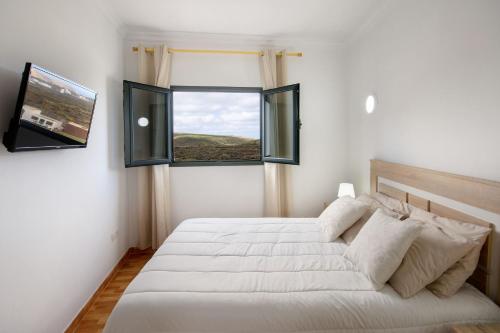 a bedroom with a large white bed and two windows at Apartamento Ye in Haría