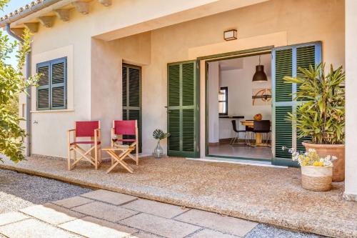 a home with a patio with red chairs and a table at Finca Sa Pradera in Se Casa Blanca
