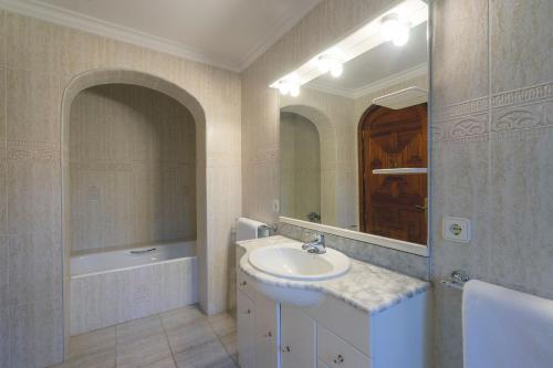 een badkamer met een wastafel, een spiegel en een bad bij Can Joan Vich ii in Santa Eularia des Riu