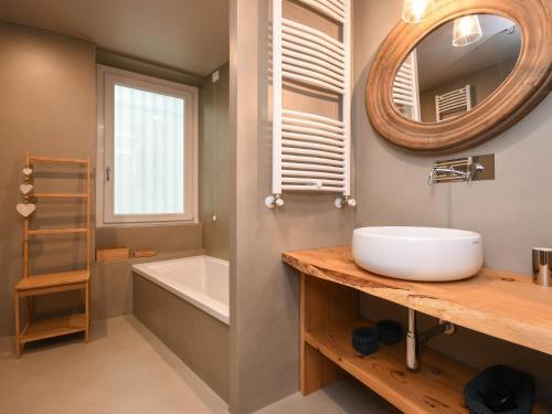 a bathroom with a sink and a tub and a mirror at Luxury modern apartment by the lake in Salò