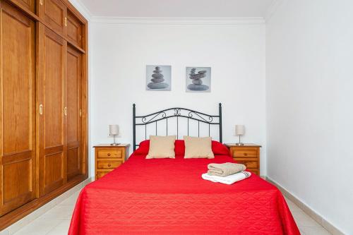 sypialnia z czerwonym łóżkiem i drewnianymi szafkami w obiekcie Apartamento Doña Alba w mieście Conil de la Frontera