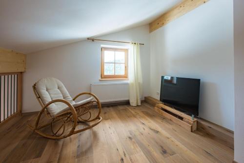 a living room with a chair and a flat screen tv at Oberprünst Hof - App. St. Sebastian in Plazzoles