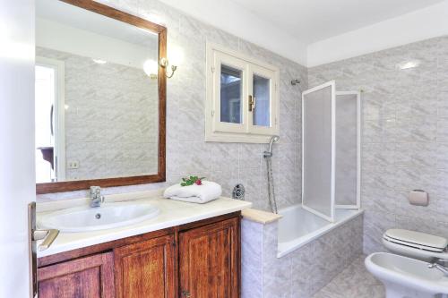 a bathroom with a sink and a toilet and a mirror at Il giardino nel sole Bilo in Capoliveri