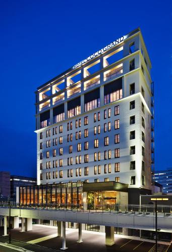 a tall white building with a bridge in front of it at Hotel Coco Grand in Takasaki