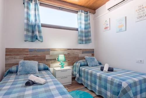 two beds in a room with a window at Casa Capricho in Vejer de la Frontera