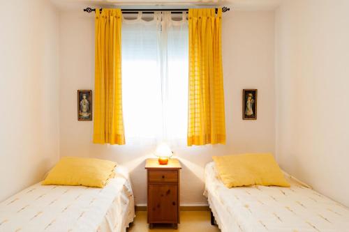 コニル・デ・ラ・フロンテーラにあるDuplex A Fontanillaの黄色いカーテンと窓が備わる客室のベッド2台分です。
