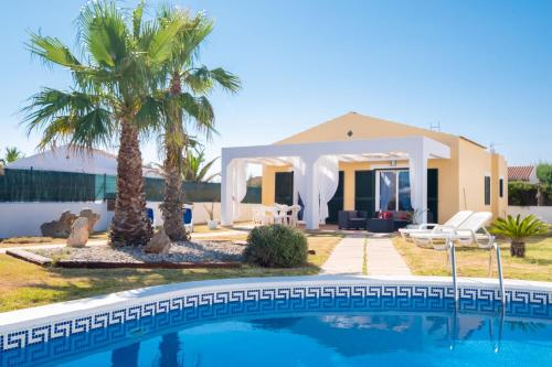 a villa with a swimming pool in front of a house at Chalet con piscina en Menorca in Cala en Bosc