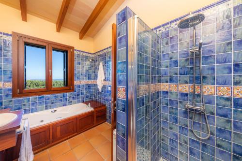 a blue tiled bathroom with a tub and a shower at Cas Pobler in Manacor