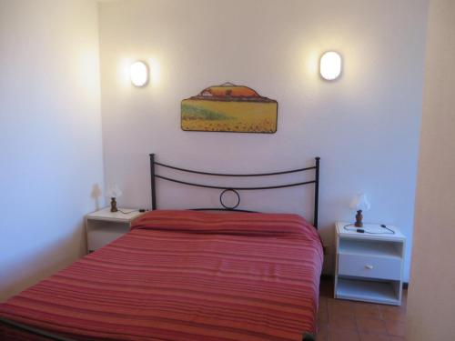 una camera da letto con un letto con una coperta rossa e due comodini di Accu is Prezzus tipo C1 fronte mare a Villasimius