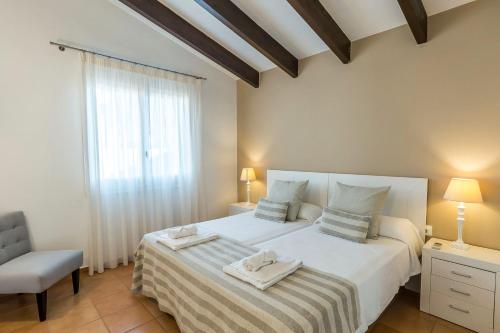a bedroom with a bed and a chair and a window at Villa Mariola in Binibeca