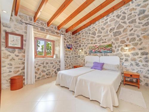 een slaapkamer met een bed en een stenen muur bij Mamici in Capdepera