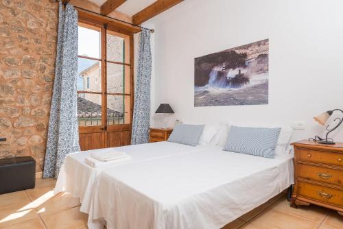 a bedroom with a white bed and a large window at Sa Fusteria in Sóller