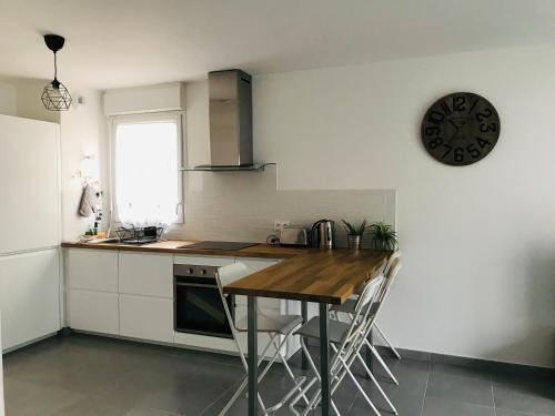 cocina con mesa y reloj en la pared en Swann Disney Appartement, en Montévrain