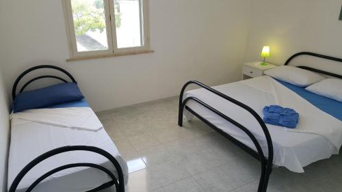 a bedroom with two beds and a window at Trilocale con doppio giardino 9 in Torre dell'Orso