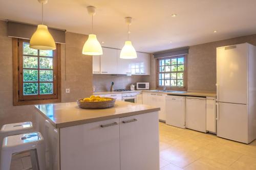 a kitchen with white cabinets and a bowl of fruit on a counter at Casa Mamita Ibiza in Sant Jordi
