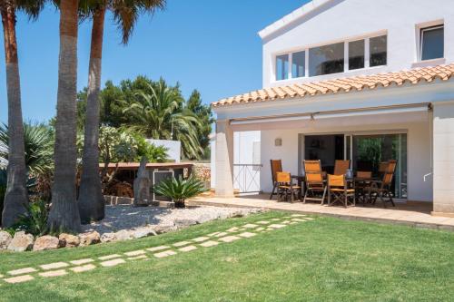 a white house with palm trees and a patio at Abatzer in Ciutadella