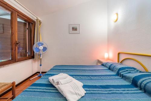 ヴィッラシミーウスにあるAccu is Prezzus Villetta B mare 50mのベッドルーム1室(青いシーツとファン付きのベッド1台付)