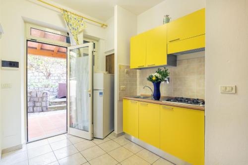 a kitchen with yellow cabinets and a door to a patio at Simona Giardino in Fetovaia