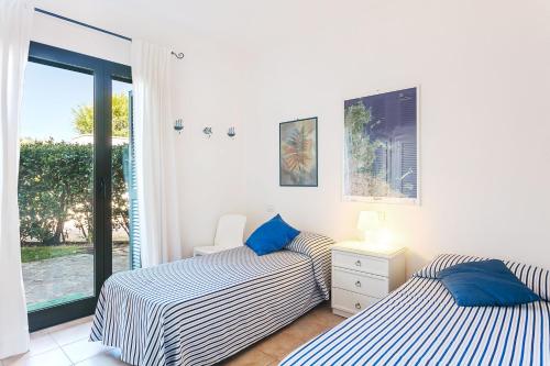 due letti in una stanza con finestra di Residenza Fiorella a San Pantaleo