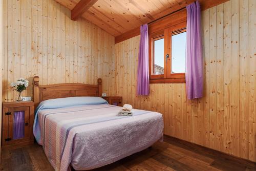 a bedroom with a bed and a window with purple curtains at Las tres hermanas in Conil de la Frontera