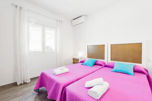 een slaapkamer met een groot roze bed met 2 kussens bij Apartamento La Higuera 1 in Conil de la Frontera