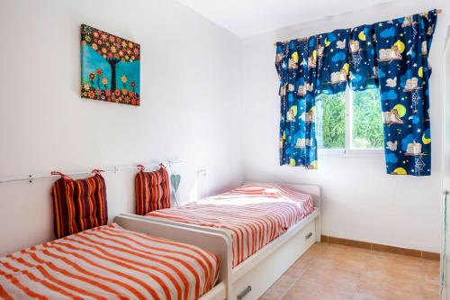 two twin beds in a room with windows at Villabella in Cala Pi