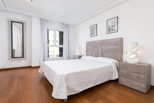 a white bedroom with a large bed and two windows at Marítimo 46 in Alcudia