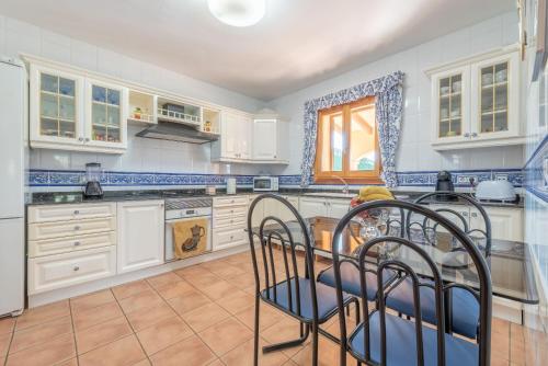a kitchen with white cabinets and a table and chairs at Solluna in Son Servera