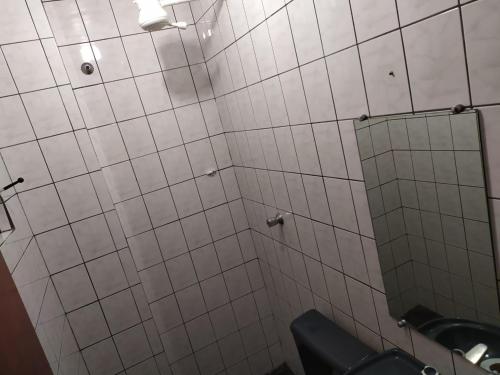 a white tiled bathroom with a mirror and a toilet at Hotel Dueto in São Bernardo do Campo