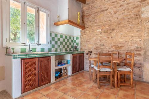 a kitchen with a table and chairs and a stone wall at Es Rafal Roig - Es Cestador in Sant Llorenç des Cardassar