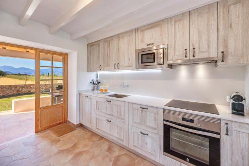a kitchen with wooden cabinets and a large window at Sa Vinya Jove in Biniali