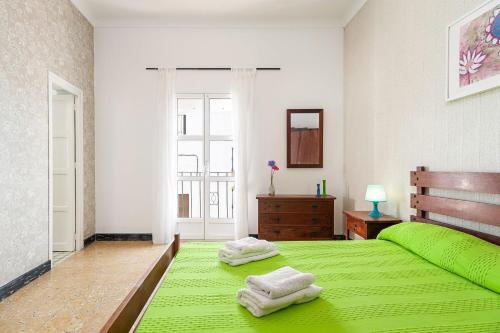 a bedroom with a green bed with towels on it at Apartamento Nicolas Only Families in Conil de la Frontera
