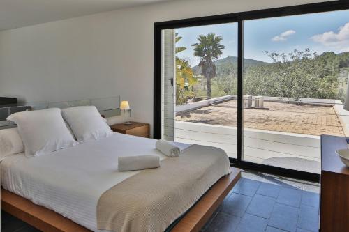 ein Schlafzimmer mit einem großen Bett und einem großen Fenster in der Unterkunft Sa Plana d´en Miquel in Sant Joan de Labritja