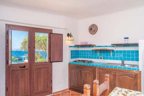 - une cuisine avec des placards en bois et du carrelage bleu dans l'établissement Monolocale Melograno, à Palau
