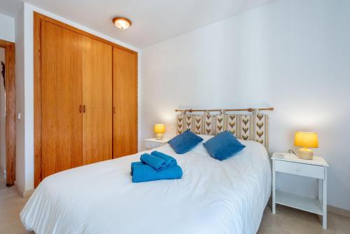 a bedroom with a white bed with blue pillows on it at Apartamento con vistas a la montaña in Sóller
