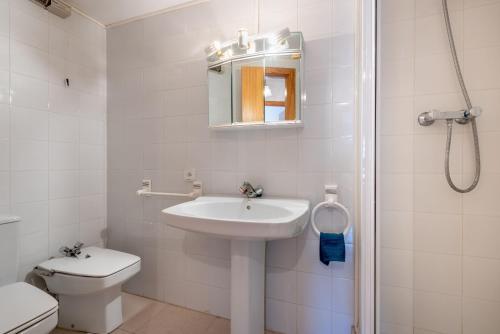 La salle de bains blanche est pourvue d'un lavabo et de toilettes. dans l'établissement Apartamento Oliver, à Sóller