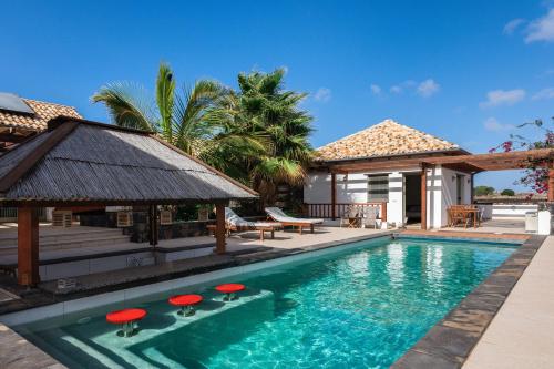 una piscina con taburetes rojos junto a una casa en Villa Annunaki, en Lajares