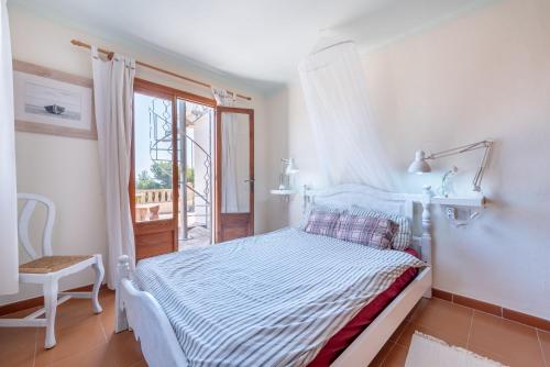 a white bedroom with a bed and a window at Can Cancus in Capdepera
