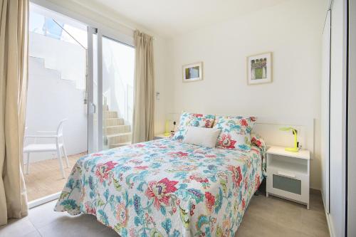 Un dormitorio con una cama con colcha floral y una ventana. en Villa Xana, en Playa Blanca