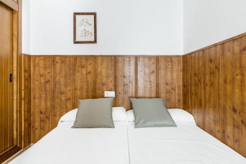 a bedroom with a white bed with wood paneling at Estudio Lila in Conil de la Frontera