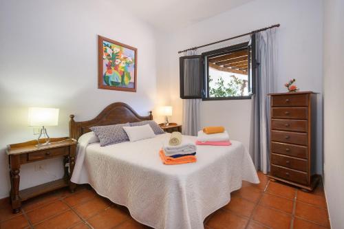 a bedroom with a bed and a dresser and a window at Finca La Rubina in Teguise