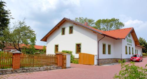 ein weißes Haus mit orangefarbenem Dach und einem Zaun in der Unterkunft Hotel Na Statku Mirošov in Mirošov