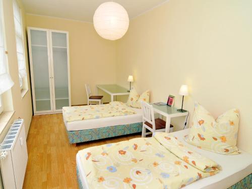 a room with two beds and a table with a desk at Pension Müllers Alte Backstube in Reichenbach im Vogtland