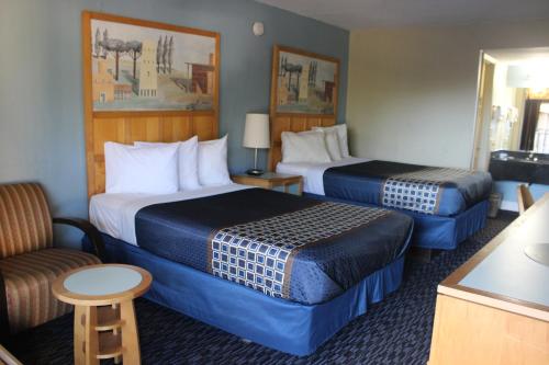 a hotel room with two beds and a chair at Tampa Inn Near Busch Gardens in Tampa