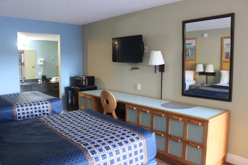 a hotel room with two beds and a mirror at Tampa Inn Near Busch Gardens in Tampa