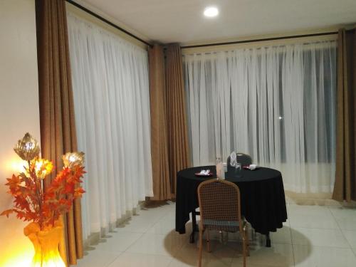 a table and chairs in a room with curtains at Lantana Comfy in Kakamega