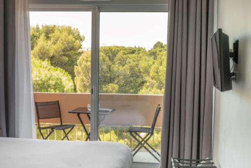 a room with a bed and a balcony with a table and chairs at Best Western Hôtel des Thermes - Balaruc les Bains Sète in Balaruc-les-Bains