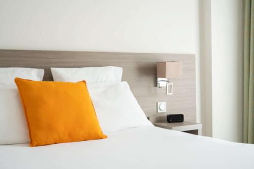 a white bed with an orange pillow on it at Best Western Hôtel des Thermes - Balaruc les Bains Sète in Balaruc-les-Bains