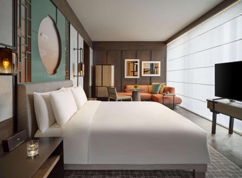 a bedroom with a large white bed and a living room at Park Hyatt Shenzhen in Shenzhen